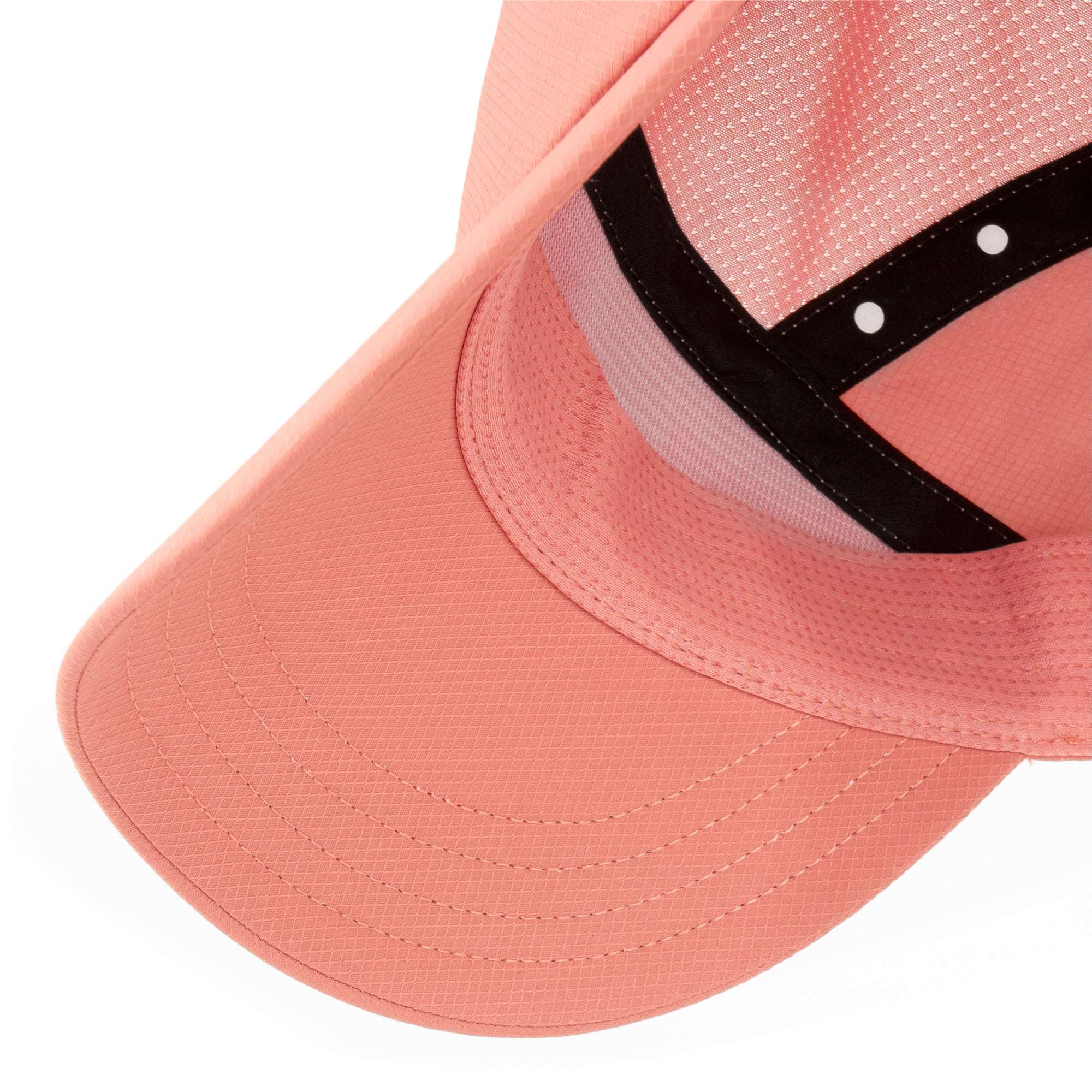 Peach-pink Ciele cap with curved brim and black side panel, perforated mesh fabric