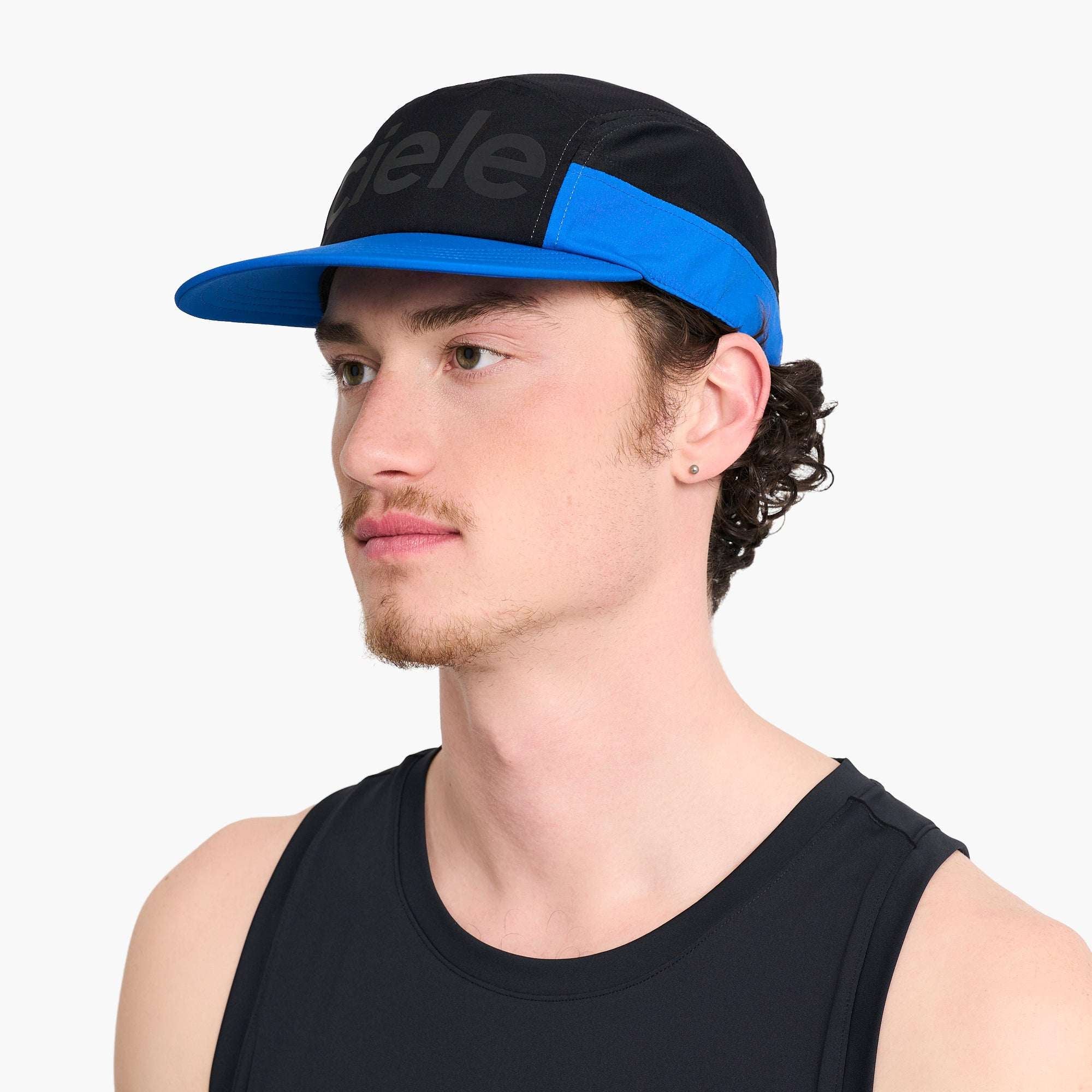Side view of a Ciele running cap on model with black crown, blue front stripe, and curved brim