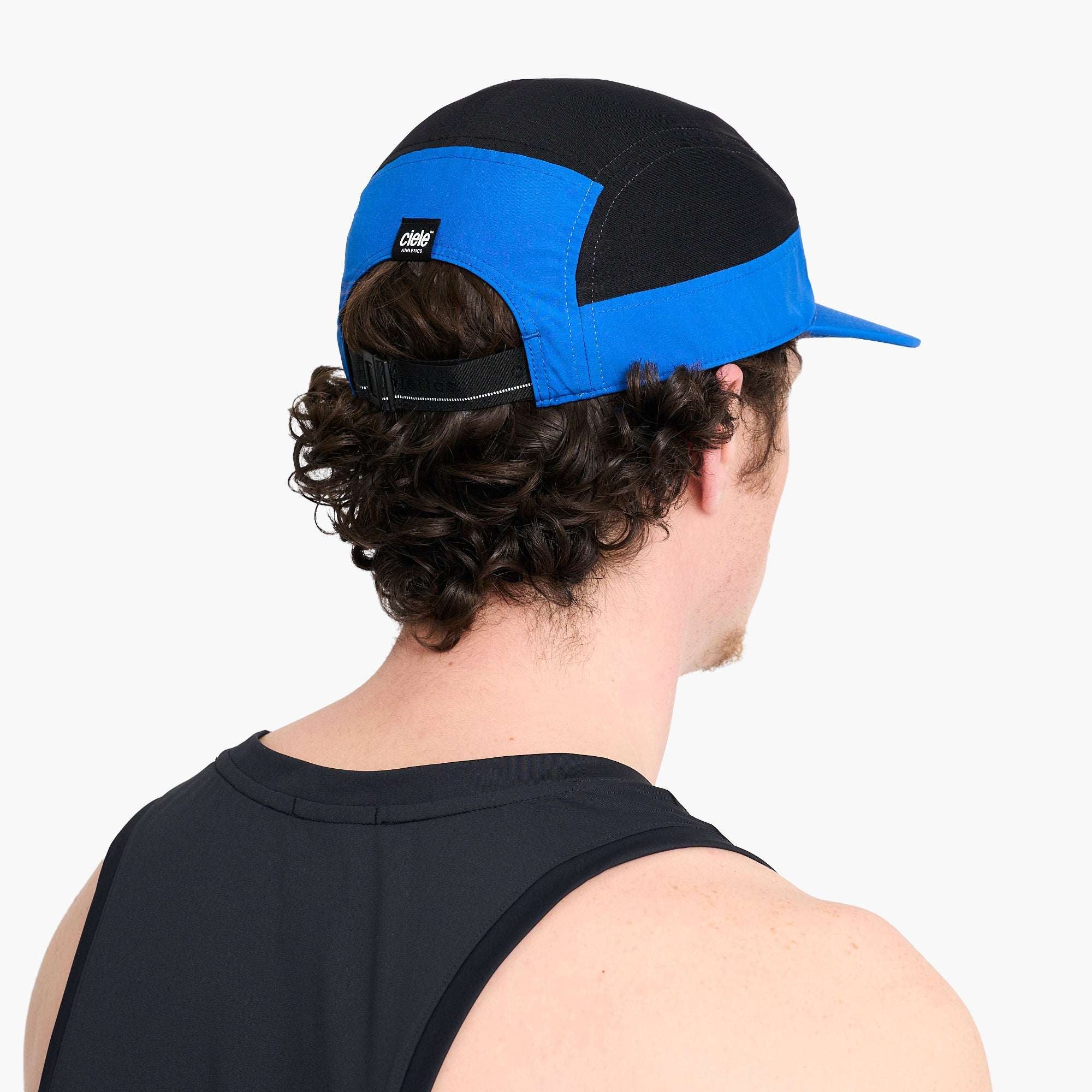 Back view of black and blue Ciele running cap with adjustable strap and stitched seams