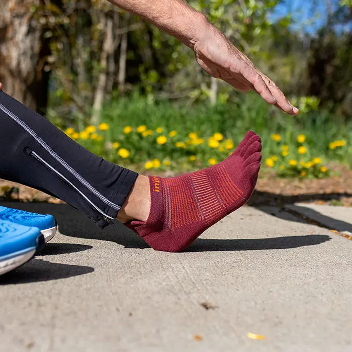 Injinji Mahogany no-show toe-separator sock on foot, ribbed pattern and logo.